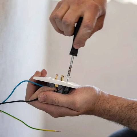 Person using screwdriver to fix electrical outlet, highlighting use of machine screws in installations