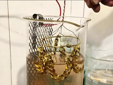 Jewelry in High Concentration 24K Gold Plating Bath Solution 100ml being electroplated, showing gold chain in beaker setup.