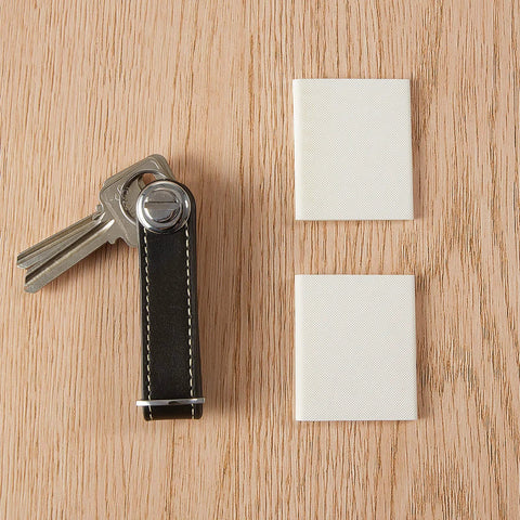 Door corner seals, white foam self-adhesive blocks for door weather sealing; two patches on wooden surface.