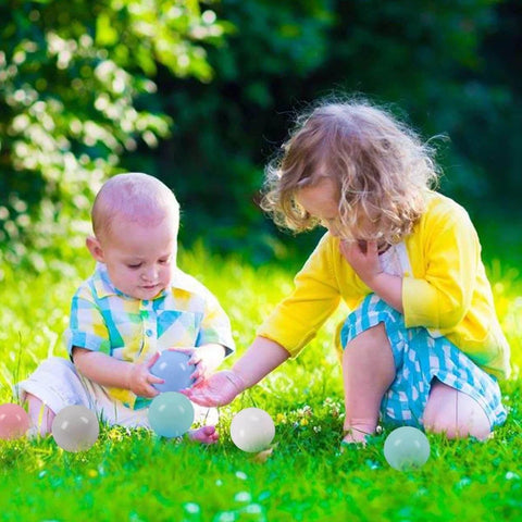 Kids playing with 50 Balls Soft Plastic Ball Pit Balls for Kids in pastel macaron colors on grass, gift for baby toddler birthday Christmas.
