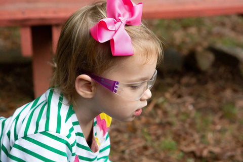 Child wearing Kids Safety Glasses ANSI Z87.1 EN166 Certified Impact Resistant Clear Lenses with pink bow, side view