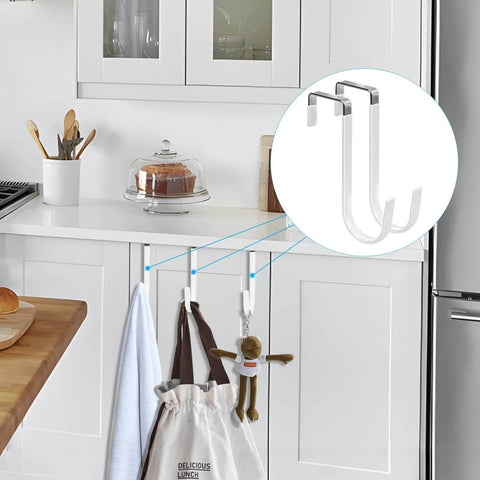 Over-cabinet door hooks in a kitchen holding towels and a bag