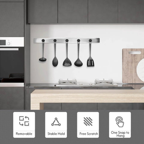Modern kitchen with wall-mounted utensil holder, four black cooking utensils hanging above a counter, focus on minimalist design and functionality.