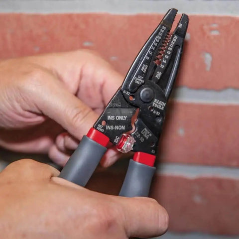 Kurve Wire Stripper Crimper Cutter Multi Tool For 10-26 AWG Solid And 12-28 AWG Stranded Wire in use against a brick wall