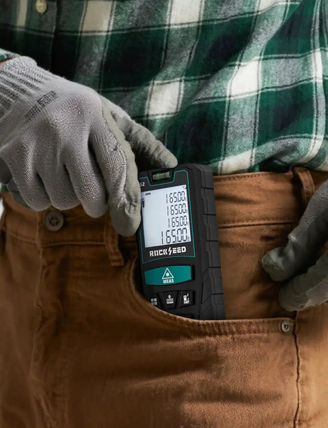Person holding compact laser distance meter with dual bubble levels in a pocket, featuring backlit LCD for measurements on job sites.
