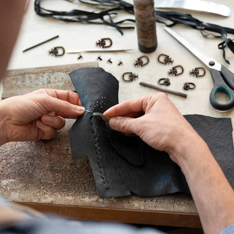 Hands stitching leather using 12 Pcs Bronze D Ring Studs With Ball Head Buttons And Rivets Set for leather crafting projects, tools visible.