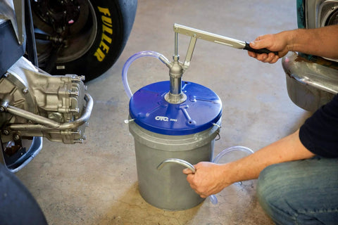 Person using OTC 2352 Lever Action Bucket Pump on a 5-gallon pail in a garage setting