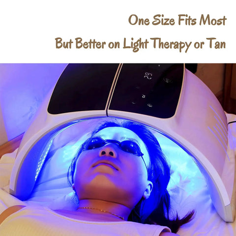 Person wearing see through safety goggles under tanning light device with 'One Size Fits Most' text.