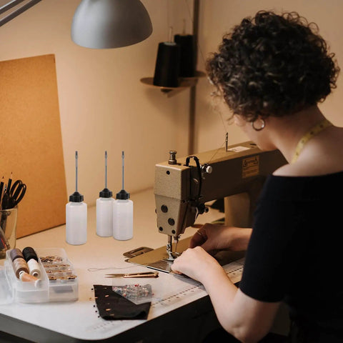 Woman using sewing machine with long mouth nozzle oil bottles for sewing machines and home tools three pack plastic oiler pots nearby