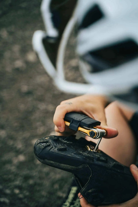Crankbrothers Multi Tool M10 Gold Compact Trailside Essential in use with bike repair, showing gold tool body and ergonomic grips.