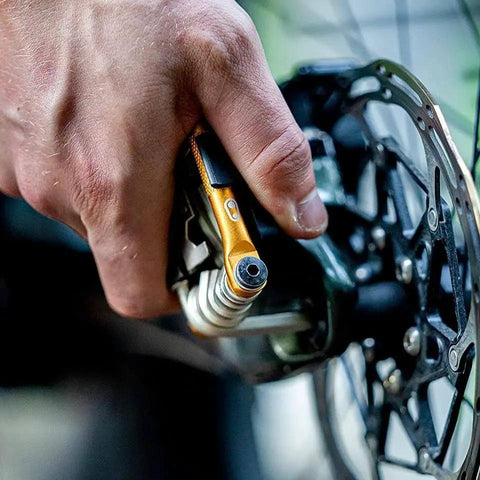 M17 Gold Bicycle Multi Tool in hand during bike repair, showing hex and spoke wrenches, close-up on ergonomic grips