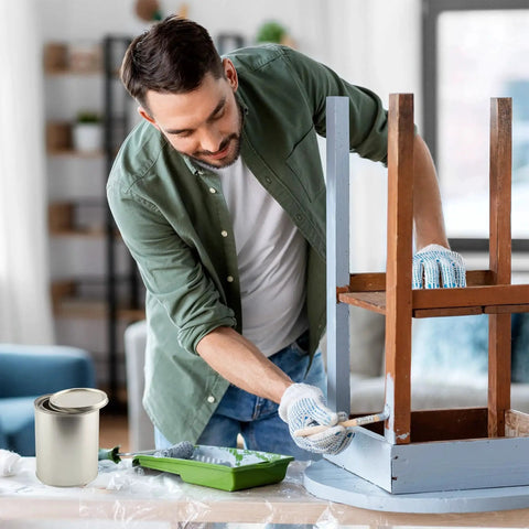 Man painting a chair with Empty Quart Paint Cans With Lids Pack Of 2 Unlined Metal Cans For Solvents in a living room setting.