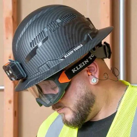 Construction worker wearing corded reusable earplugs with 25dB NRR in bright orange case for loud environments and safe fit.