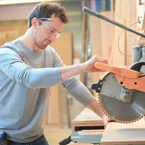 Man wearing 48 Pack Safety Glasses Clear Protective Eyewear For Work Lab Lightweight Comfort operating a power saw.