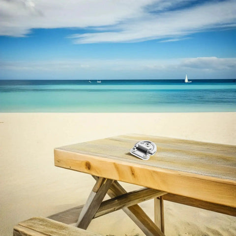 Folding marine-grade stainless steel D-ring tie-down anchor on a wooden beach table
