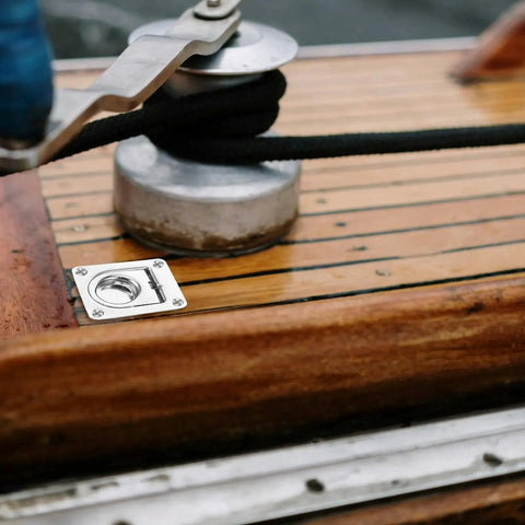 Installed stainless steel flush pull ring plate on wooden boat deck (65x56mm) with recessed ring and four screws.