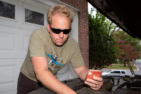 Man wearing UV Protection Safety Goggles With 99 Percent UV Impact Resistant Clear Lenses working on car engine outdoors.