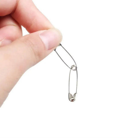 Hand holding a metal safety pin from the Bulk 1000-Piece 1.1-Inch Clips Tool Kit With Assorted Decorative Pins For Sewing And Crafting.