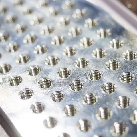 Close-up of a metallic plate with threaded holes showing use of Spiral Point Plug Threading Tap M5 x 0.8 Thread, Ground Threads H2 3 Flutes.