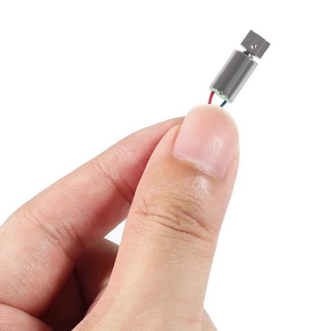 Close-up of a 6pcs DC 1.5V 3V 12000RPM 6x10mm Miniature Micro Vibrating Vibration Coreless Motor Small Electric Motors 2 Wires between fingers.