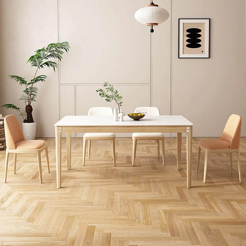 Minimalist dining room with white table, four chairs, wood floor, plants, and abstract wall art.