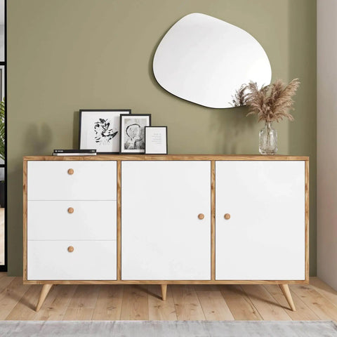 Modern sideboard with white doors and natural wood details, featuring decor items and a mirror on the wall behind.