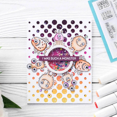 Handmade card with colorful monsters, circular sequin embellishment, and 'I was such a monster' text, on a white wooden background.