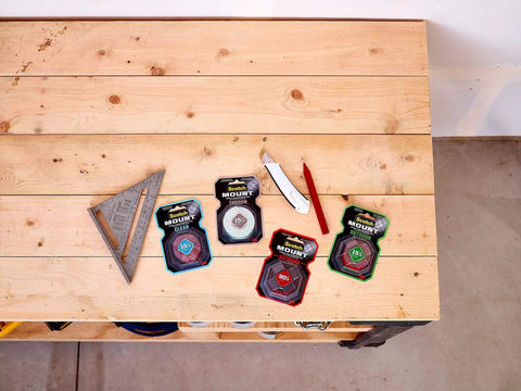 Packaged adhesive tapes on wooden bench with tools, featuring Extreme Double Sided Mounting Tape 414H for wood, metal, and concrete.