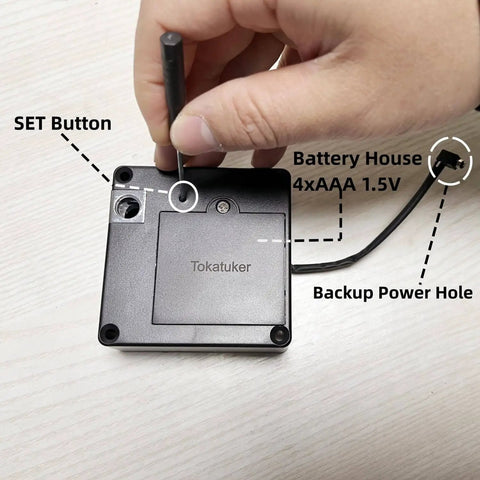 Backside view of a discreet USB powered cabinet lock with NFC and RFID access, showing set button and battery compartment on wood surface.