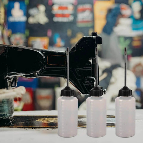 Long Mouth Nozzle Oil Bottles For Sewing Machines And Home Tools Three Pack Plastic Oiler Pots next to a sewing machine