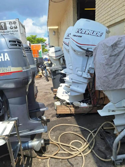 Row of outboard motors including Yamaha and Evinrude seen outside a marine workshop.
