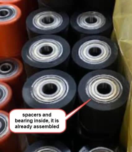 Pallet Jack Load Wheel with poly steel hub, 3 x 2.5 inch size, pre assembled, visible spacers and bearings, stacked in storage.