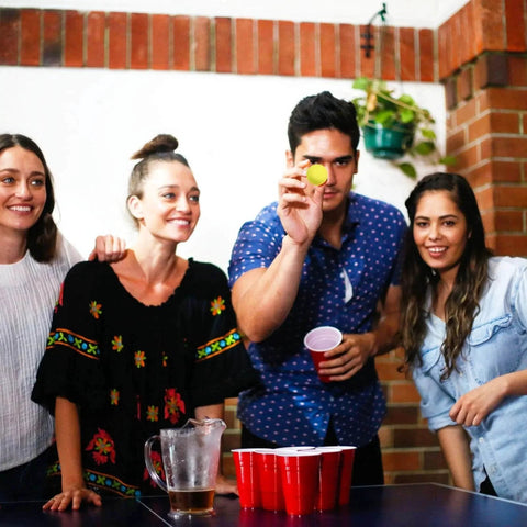 Group playing party game with 100 Pack Table Tennis Balls, 40mm Colored Plastic Balls Beer Balls Bulk; yellow ball in focus.