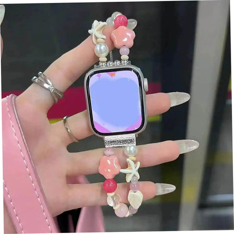 Hand holding smartwatch with decorative bead strap, featuring silver alloy adapters for seamless band swaps and style options.