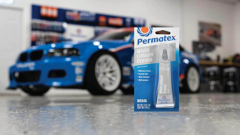 Permatex 80345 White Lithium Grease, 1.5 oz tube in packaging with a blue race car in the background.