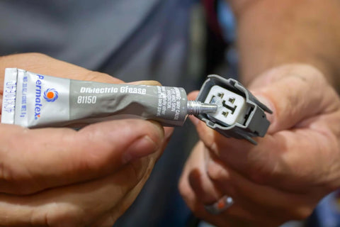 Applying Permatex 81150 Dielectric Tune-Up Grease, 0.33 oz. Tube, Silver to electrical connector in hand.