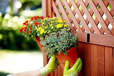 Person using Extreme Interlocking Fasteners That Bond On Contact, 4 Strips 1 Inch By 3 Inches to mount a plant on a wooden fence.