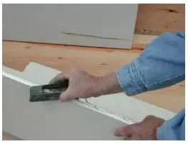 Person using Pocket Drywall And Ceiling Tile Rasp With Replaceable Blade Designed For Fine Edge Trimming Of Drywall And Tiles.
