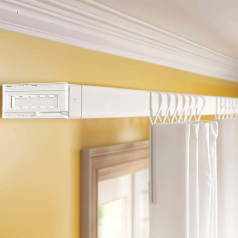Installed white drapery rod with adjustable brackets for wide pocket rods, seen in a living room setting.