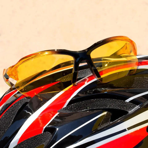 Polarized Night Vision Driving Glasses For Men With Anti Glare Yellow Lenses resting on a colorful cycling helmet.