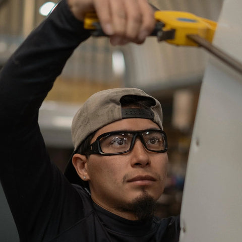 Worker wearing Brazeau Polarized Safety Glasses With 99.9 Percent UV Protection And ANSI Z87, using a tool indoors.