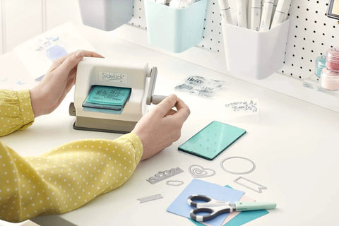 Person using Portable Die Cutting And Embossing Starter Kit For Arts And Crafts Scrapbooking And Cardmaking On The Go Sizzix Sidekick 661770 Included Compact Manual Cutter With 6.35 cm And 2.5 Inch Openings White on a desk