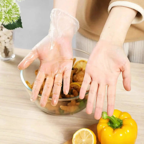 Person wearing a Powder Free Vinyl Glove 4.3 Mil Clear Latex Free for food service, preparing vegetables in a kitchen setting.