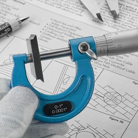 Close-up of blue micrometer measuring sheet thickness, marked 0-1 inch 0.0001in, part of Outside Micrometer Set 0 To 4 Inch 4 Piece 0.0001in Graduation Carbide Anvils Case