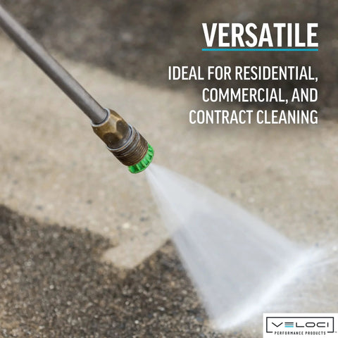 Pressure washer nozzle tip with brass body and green nozzle spraying water outdoors