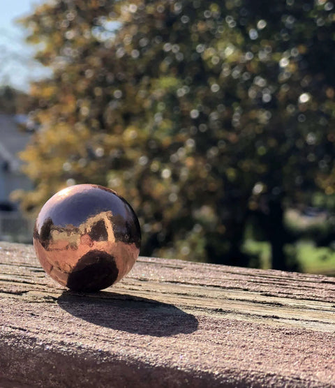 Unique Metals Pure Copper Sphere 1-1/8" for healing, decorative use, grounding, alchemical magic on wooden surface outdoors