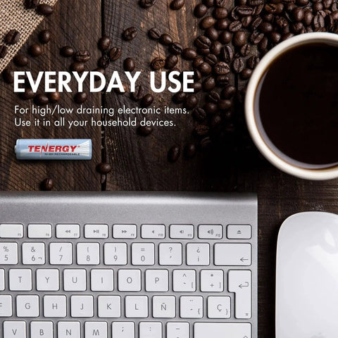 Rechargeable NiMH AA And AAA Batteries Kit with Tenergy battery beside computer keyboard and coffee cup on wooden table.