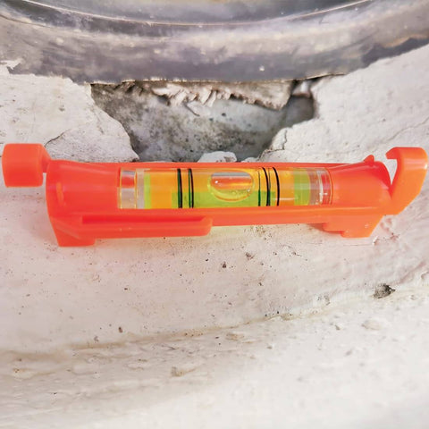 Close-up of a red acrylic line level tool placed on a stone surface, part of the Five Piece Red Hanging Line Level Set For Quick Layout.