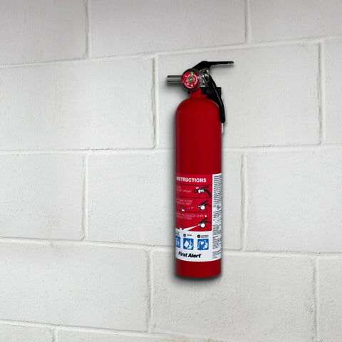 A red fire extinguisher mounted on a white brick wall with visible instructions and gauge.