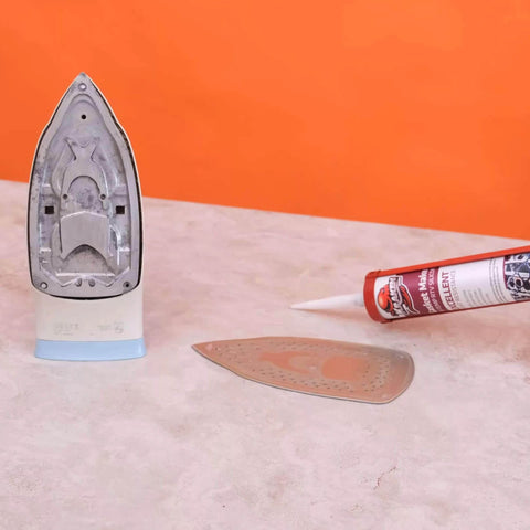 Red RTV Silicone Gasket Maker Sealant tube next to detached iron soleplate on a table, emphasizing heavy-duty automotive use